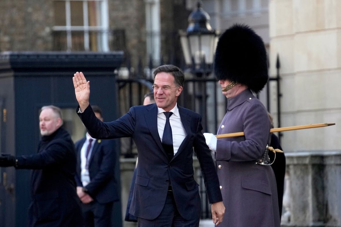 A man in a suit waves.