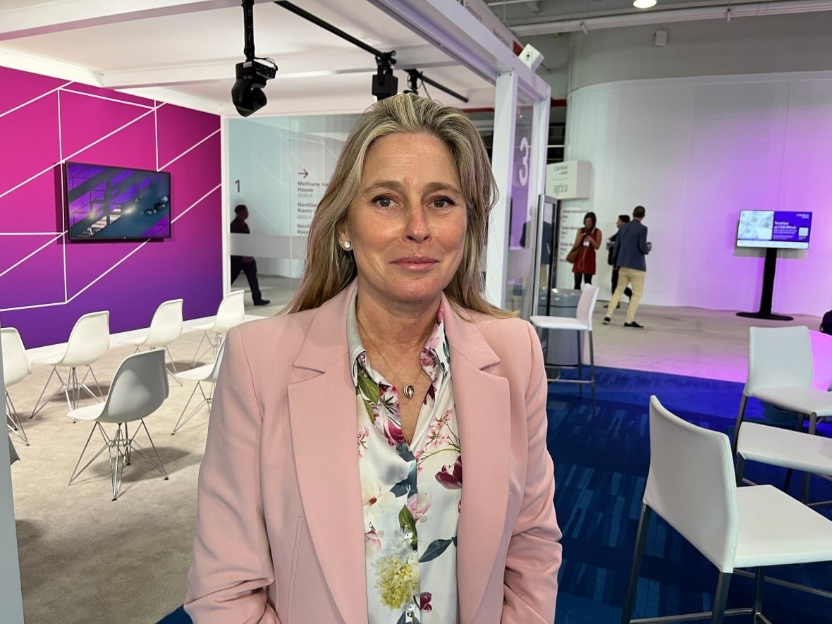 A woman in a pink suit and floral blouse is pictured on the sidelines of an energy conference in Houston.