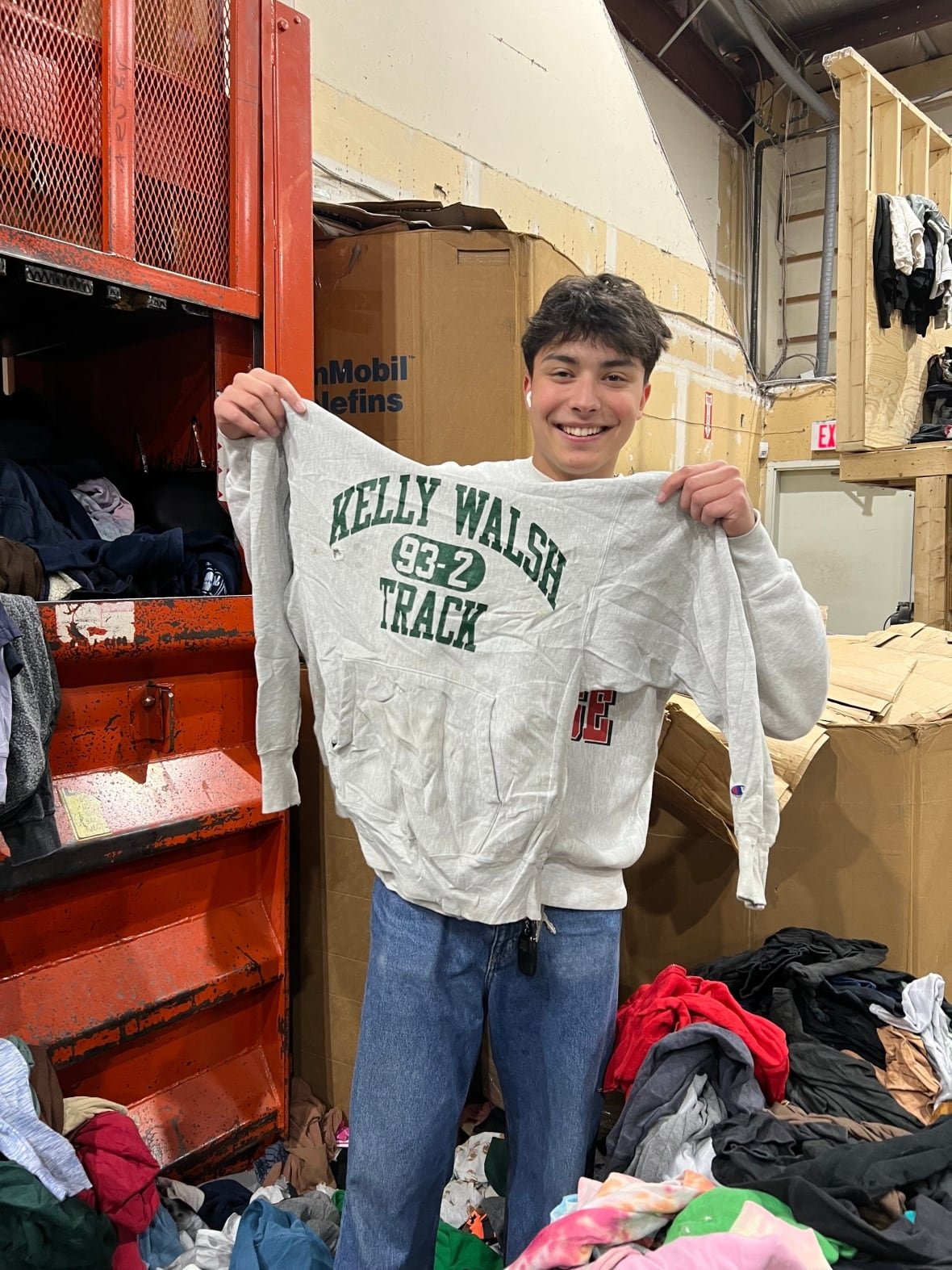 A man stands in a warehouse holding a sweatshirt.