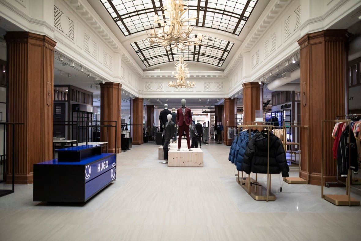 An ornate store with a mannequin, racks of jackets and no shoppers.