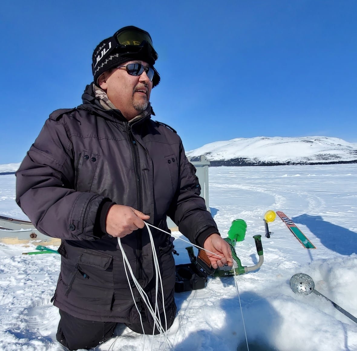 An Inuk man measures ice. 