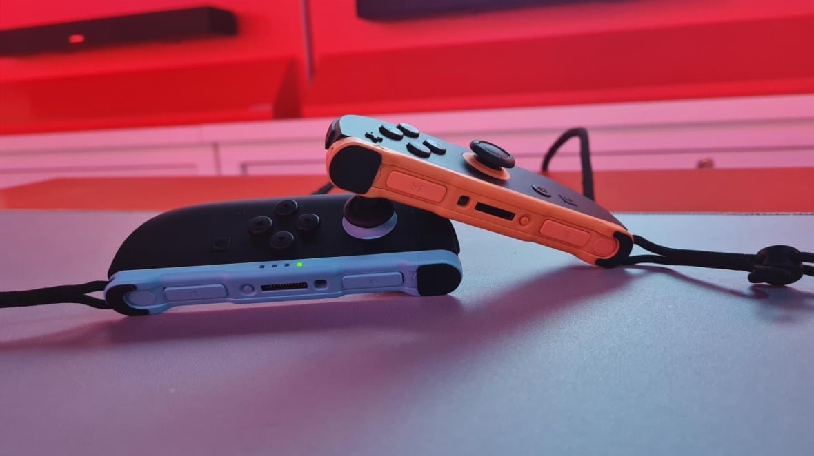 Two Nintendo Switch 2 controllers -- one red, one blue -- are displayed. 