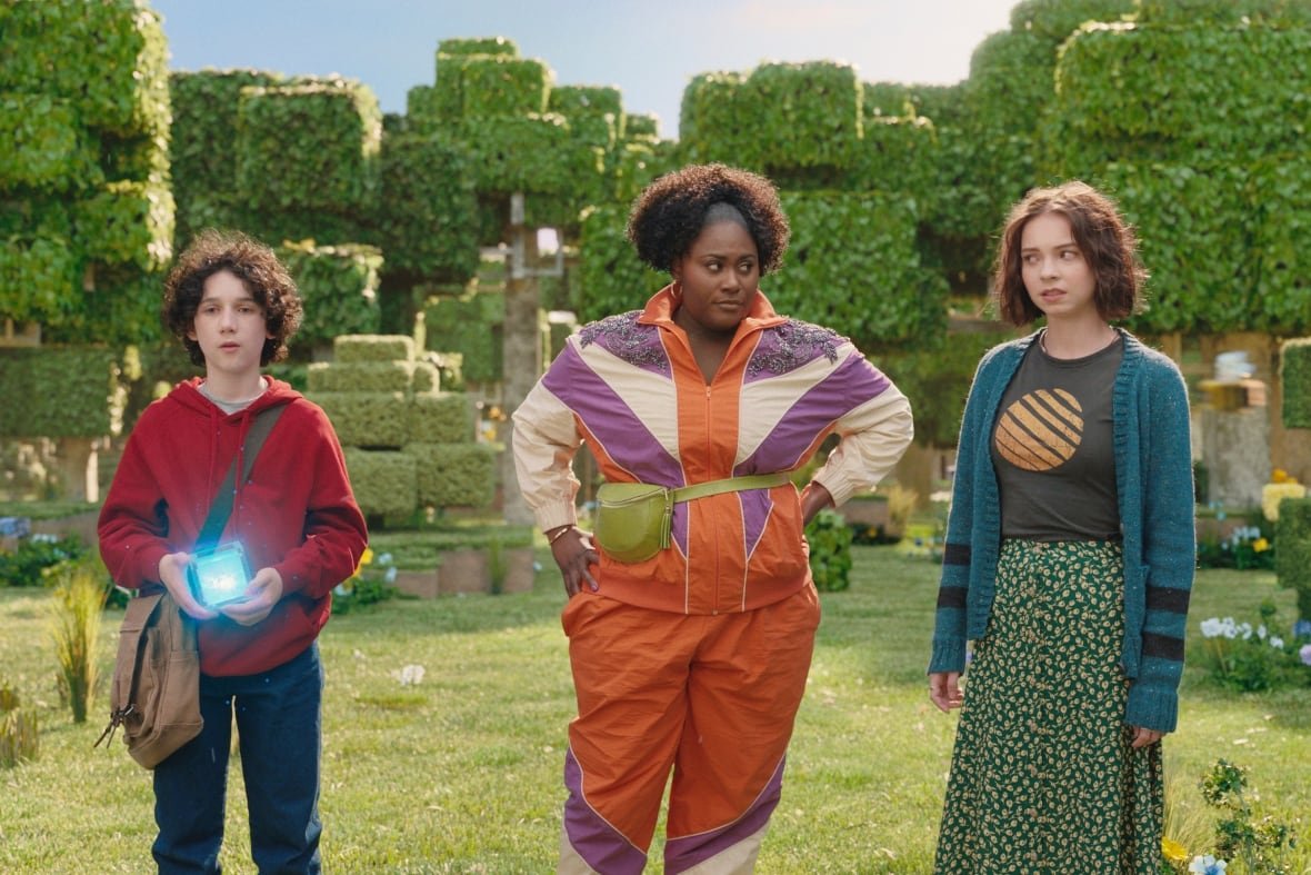 Three people stand in a CGI forest of box-shaped trees. 
