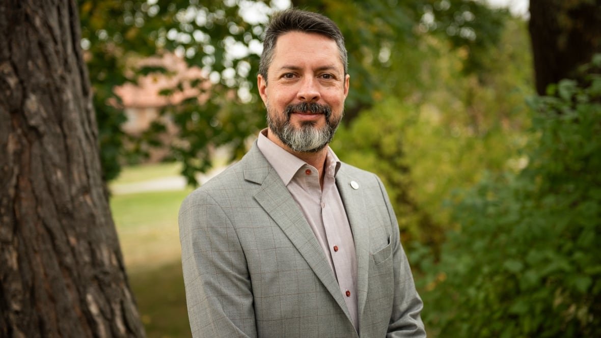 A man in a suit smiles to the camera.