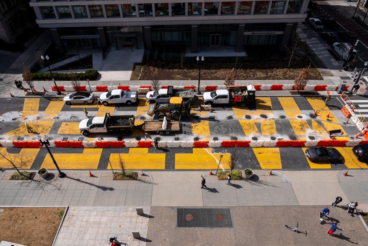 A man in a U.S.A.-themed blazer and red pants takes a cell phone photo at bottom right, as demolition begins on the Black Lives Matter mural, seen from above, Monday, March 10, 2025, in Washington. (AP Photo/Jacquelyn Martin)