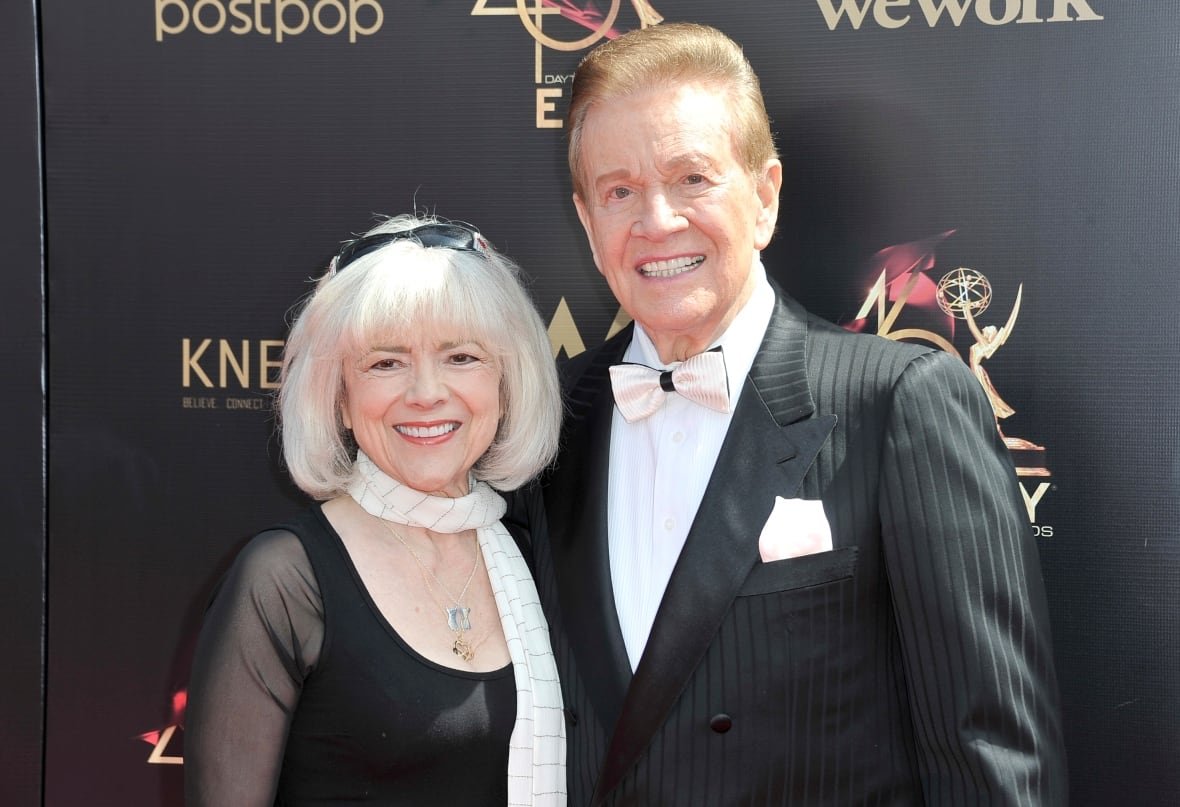 Two people smile while posing for photographs.