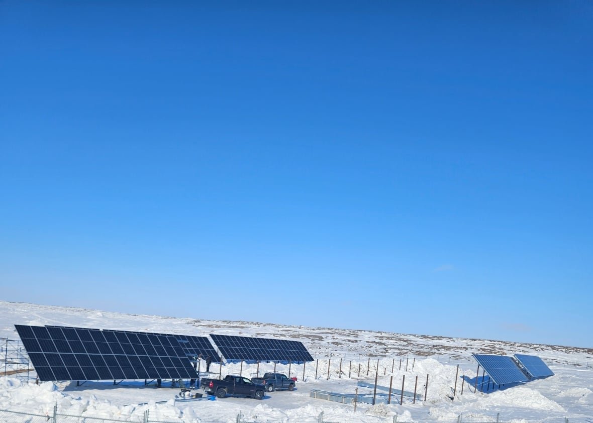 Solar panels in snowy landscape with blue sky overhead