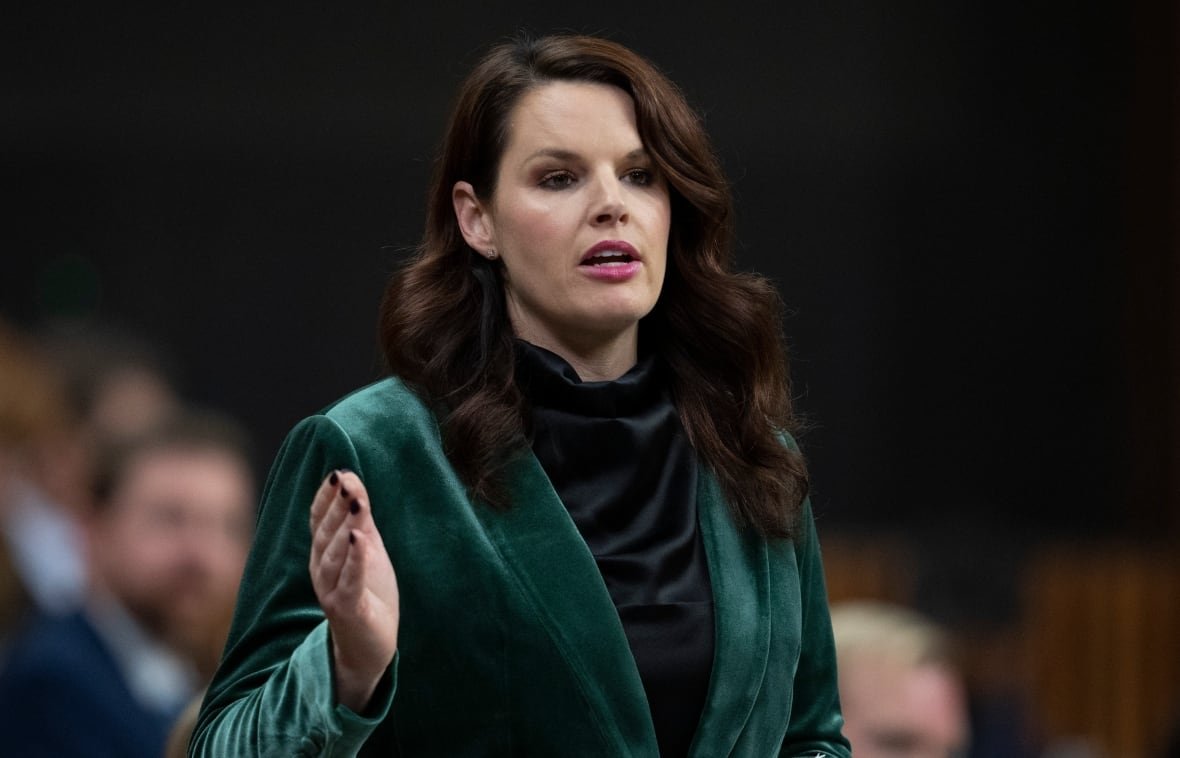 A woman wearing a green blazer speaks in the House of Commons.