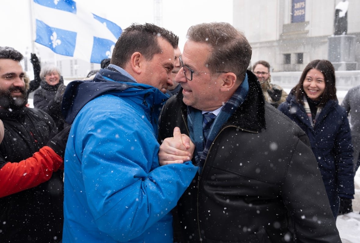 Two men embarce in a snowy setting.