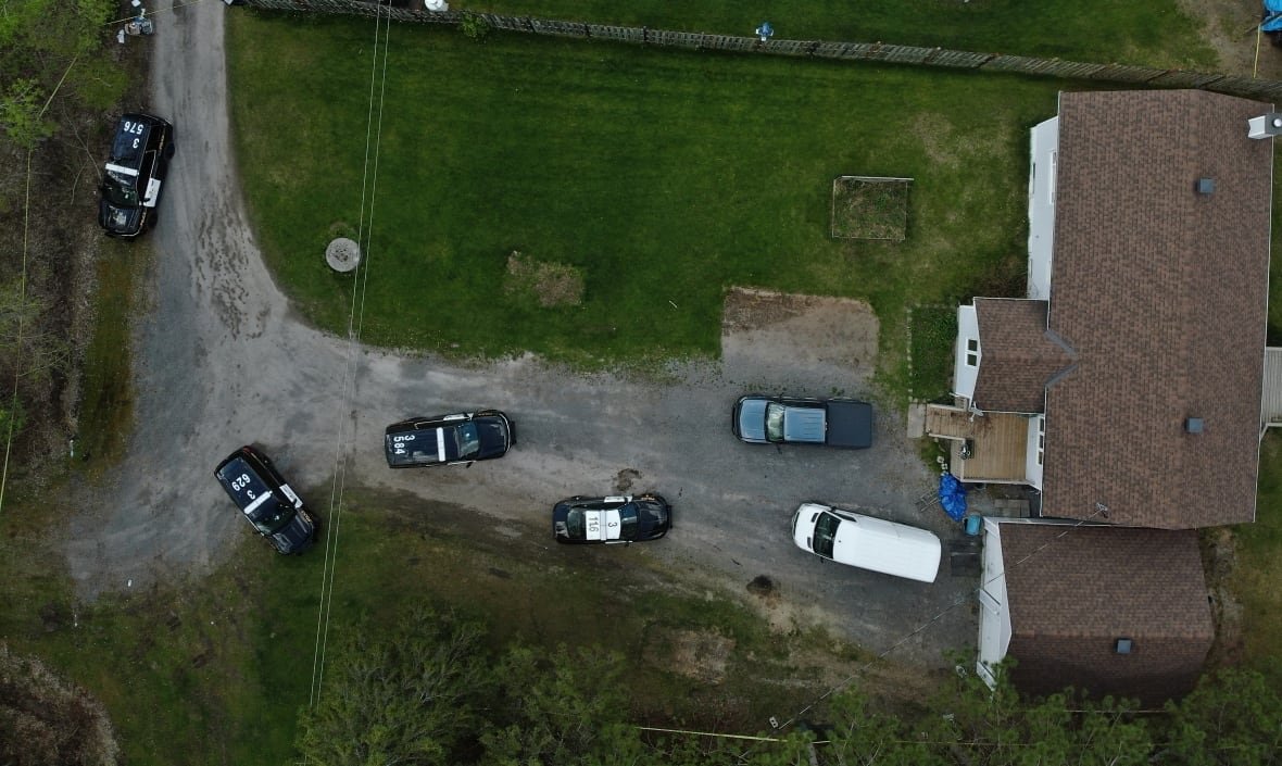 An aerial view of a house with police cruisers and other vehicles parked out front.