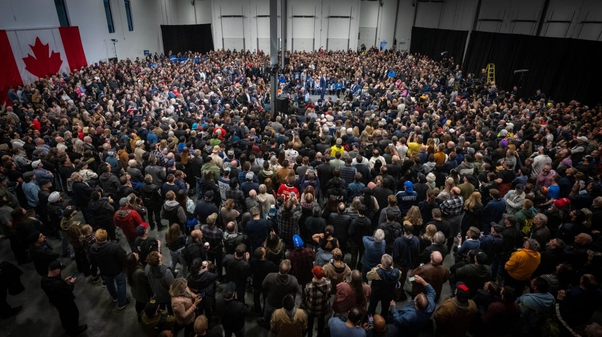 A crowd of people listen to a politician.