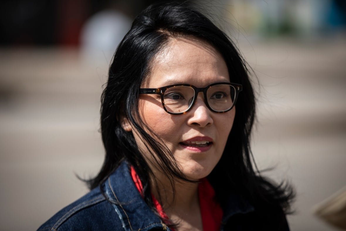 A woman, wearing glasses, pauses as the wind blows through her hair