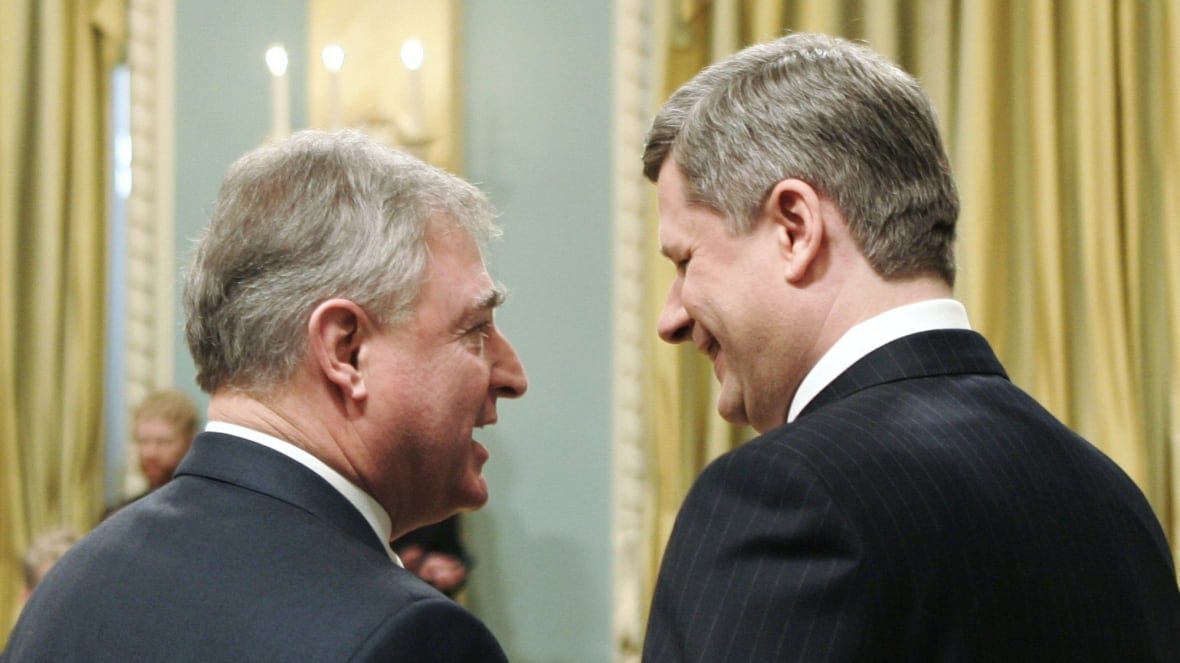 Two men with grey hair laugh and smile as they are photographed from behind. 
