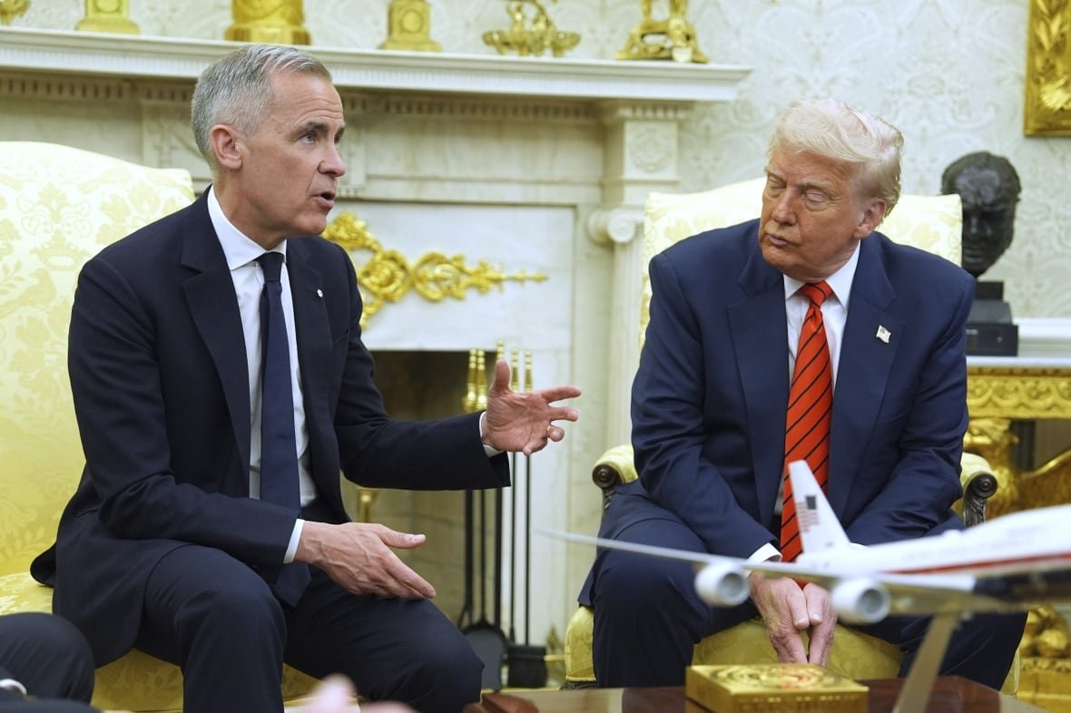 Two mean sit in an ornate room.