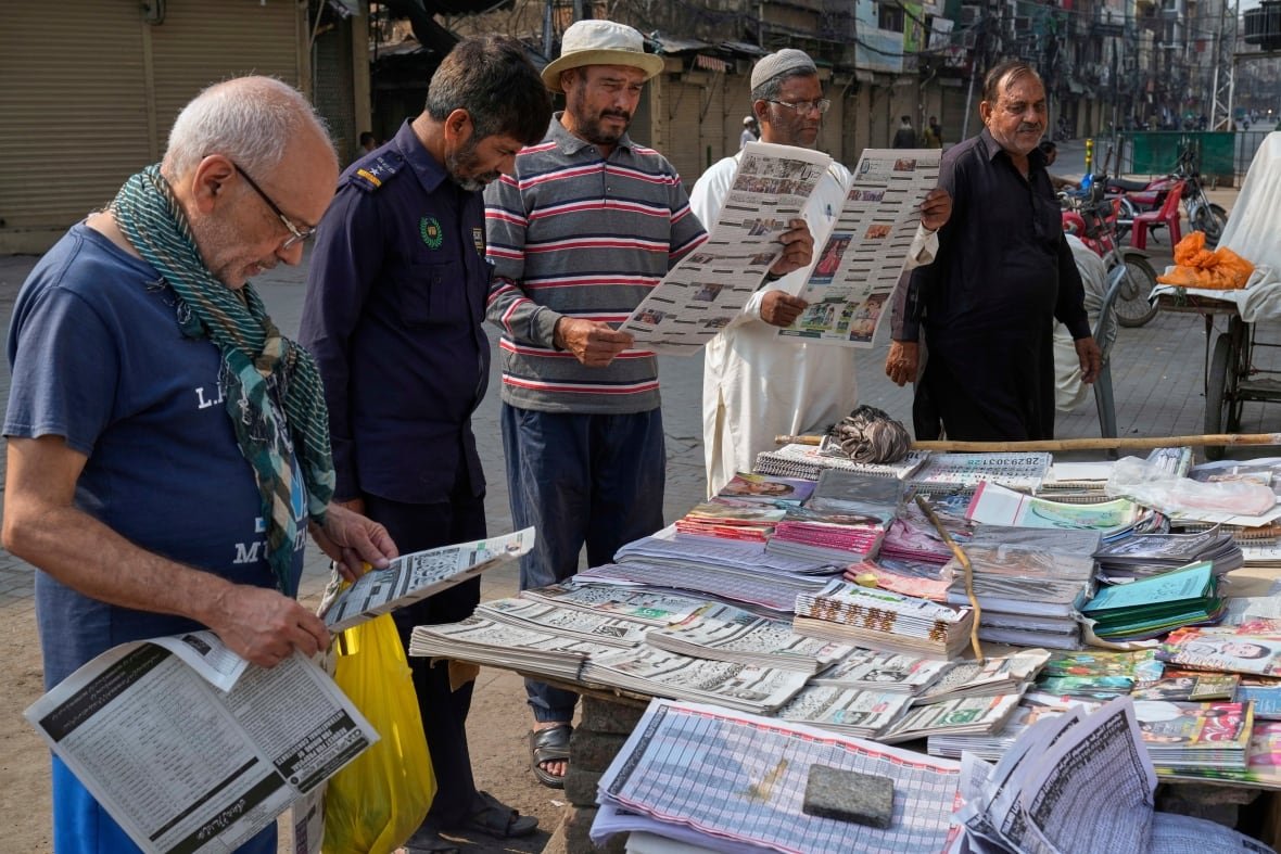 People read newspapers at a stall.