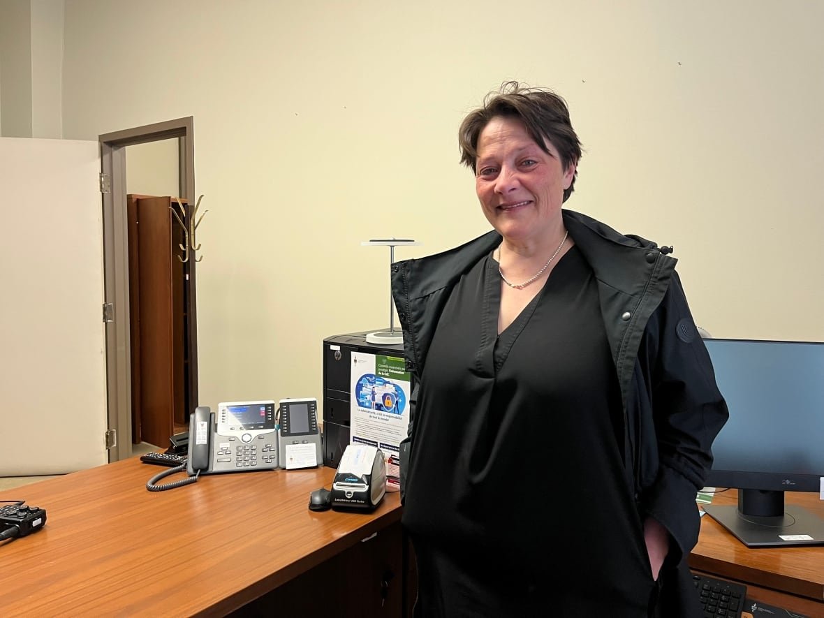 A woman with short brown hair wearing a black shirt smiles for the camera.