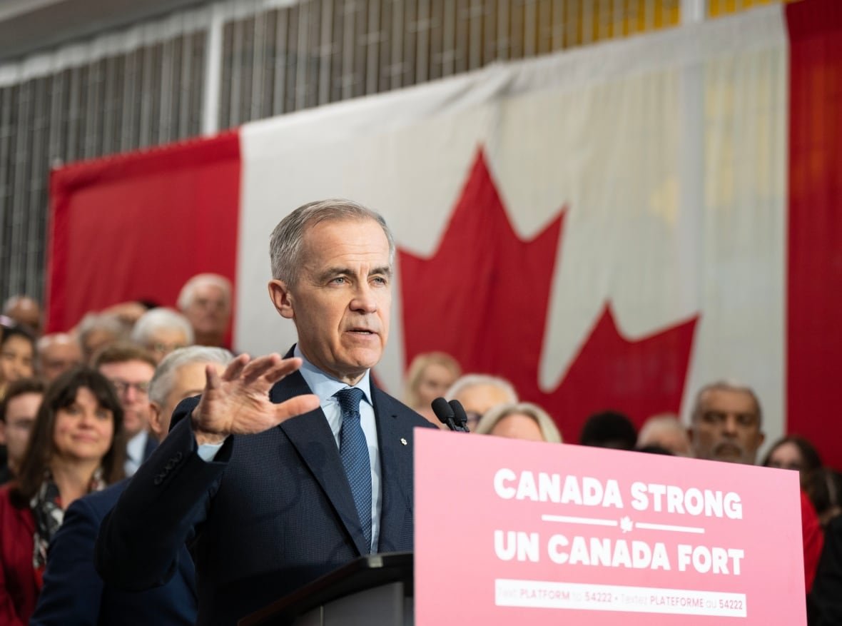 Mark Carney stands at a podium with a sign that says "Canada Strong-Un Canada Fort," with a Canadian flag hanging in the background