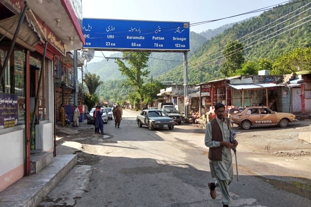 People walk on a street with mountains in the background.