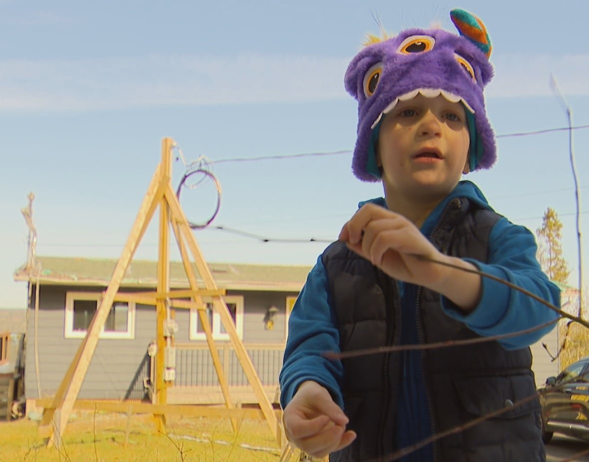 A four-year-old boy is shown playing outside.