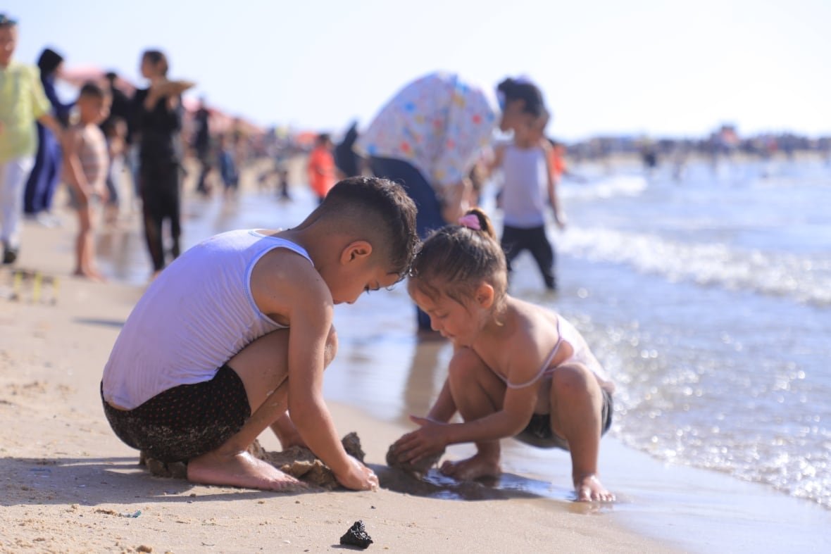 two kids play in the sand on a beach 