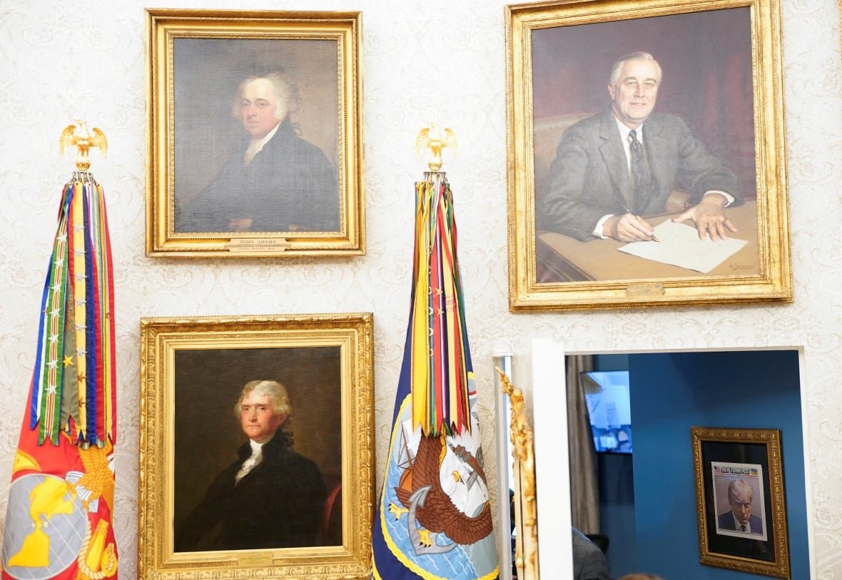 Golden framed portraits of Roosevelt, Jefferson, Adams, and a New York post cover with Trump's mug shot, on the walls of the Oval Office