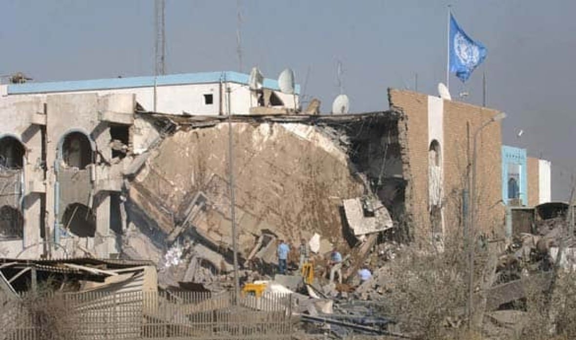 A heavily damaged building with a blue flag flying on top.