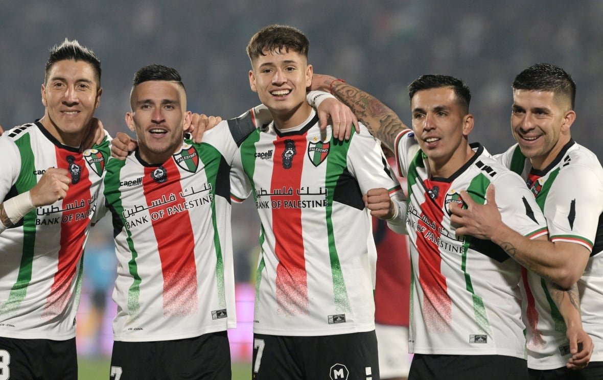 Soccer players in white, red and green jerseys celebrate a goal. 