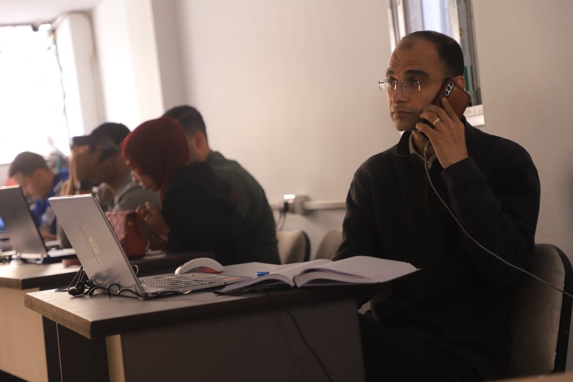 a man sits at a desk next to other people