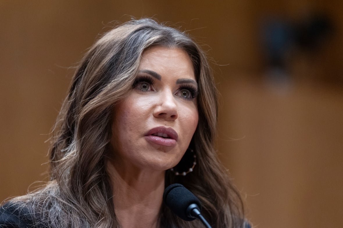 A woman with brown hair is shown seated, in a closeup.