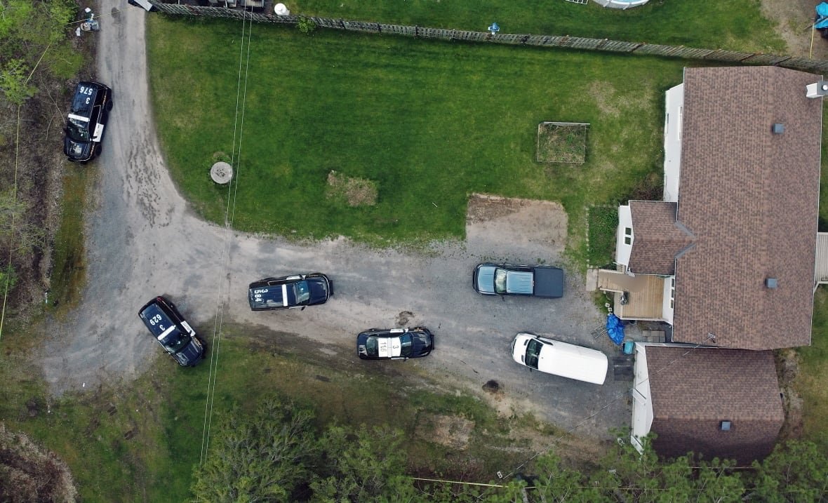 An aerial view of a house with police cruisers and other vehicles parked out front.