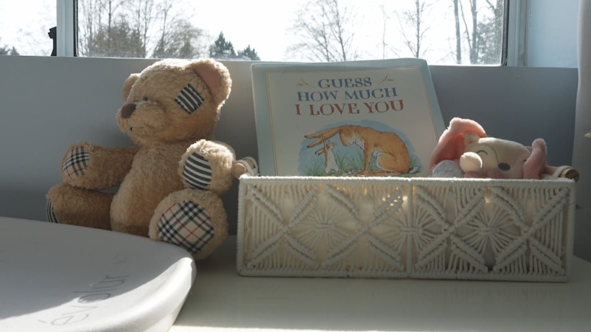A teddy bear is propped beside a diaper change pad and a book titled 'Guess How Much I Love You.'