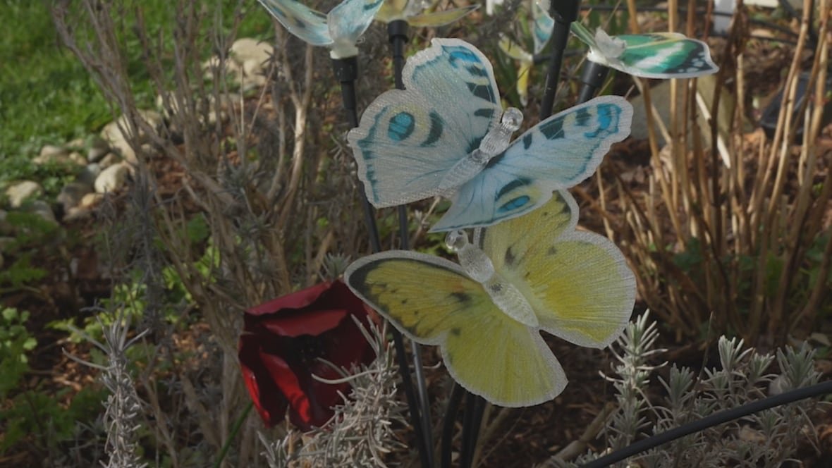 Yellow, blue and red butterfly decorations in a garden.