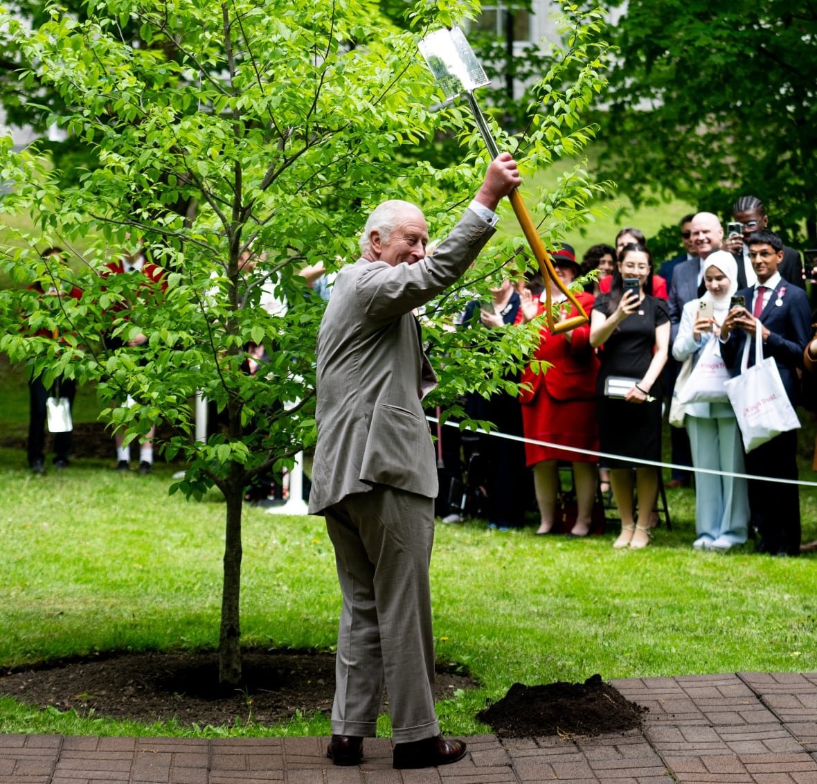 King Charles waves a shovel used during a tree planting ceremony at Rideau Hall in Ottawa, on Monday, May 26, 2025.