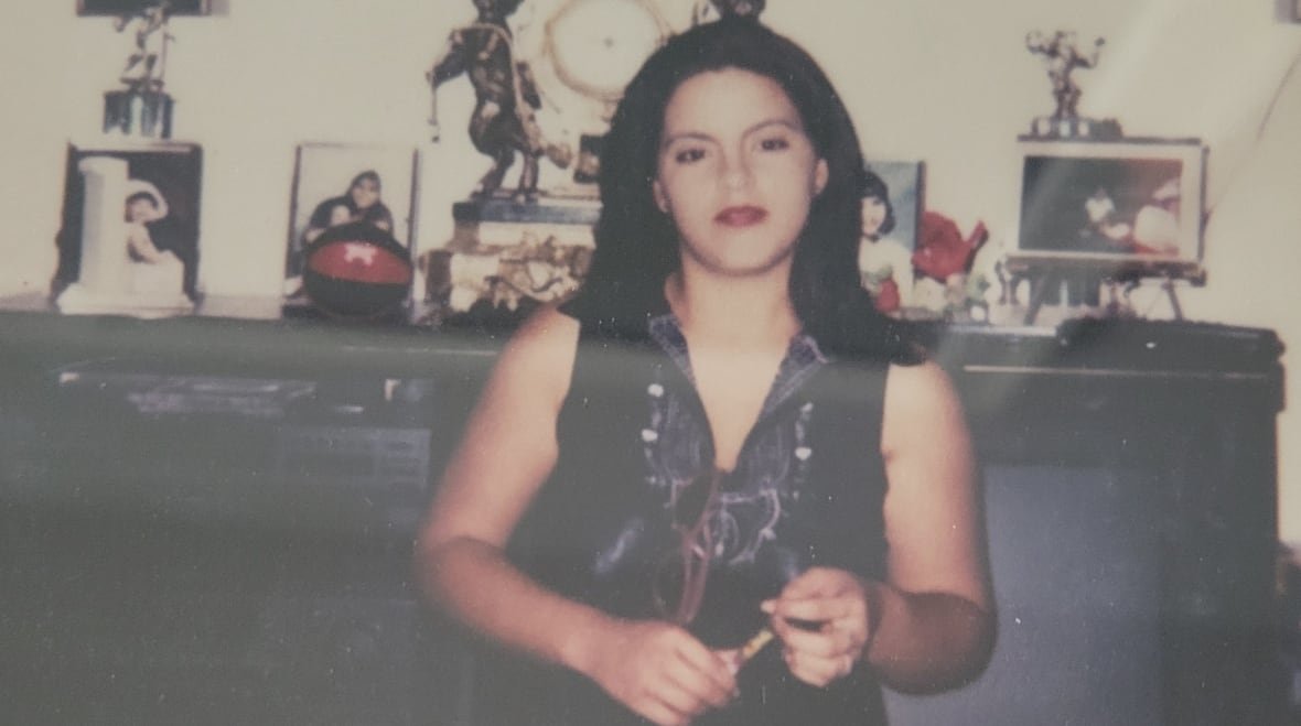 A woman with long dark hair smiles while standing in front of a piano