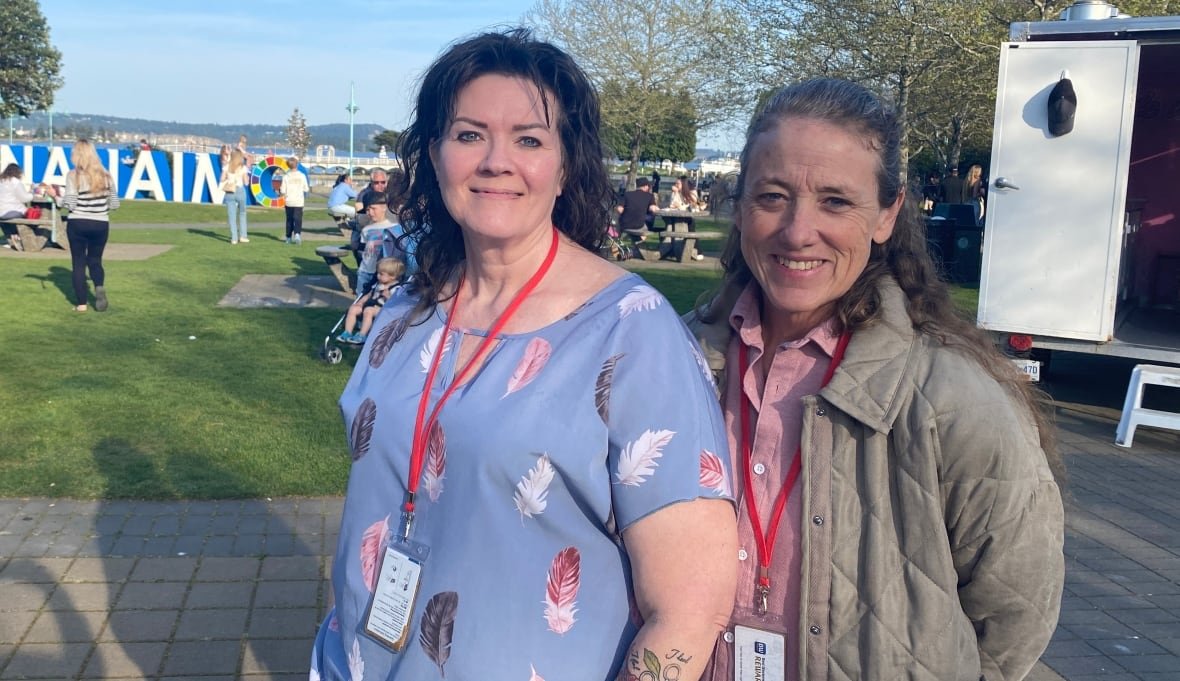 Two women smile in a park on a sunny day.