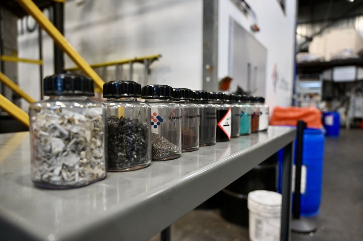 Jars containing various substances are lined up on a table at an industrial plant. 