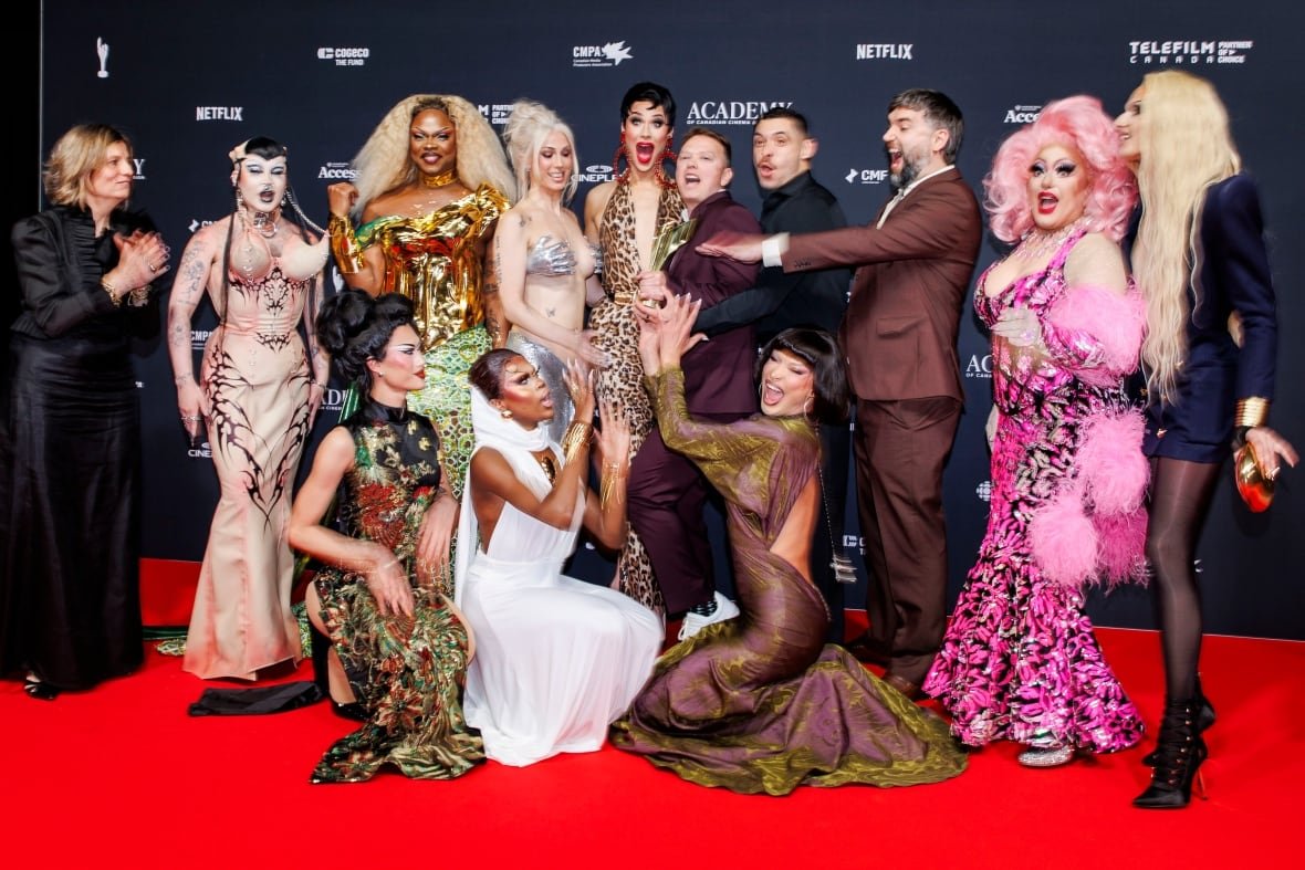 A group of people wearing ballroom gowns pose with a trophy.