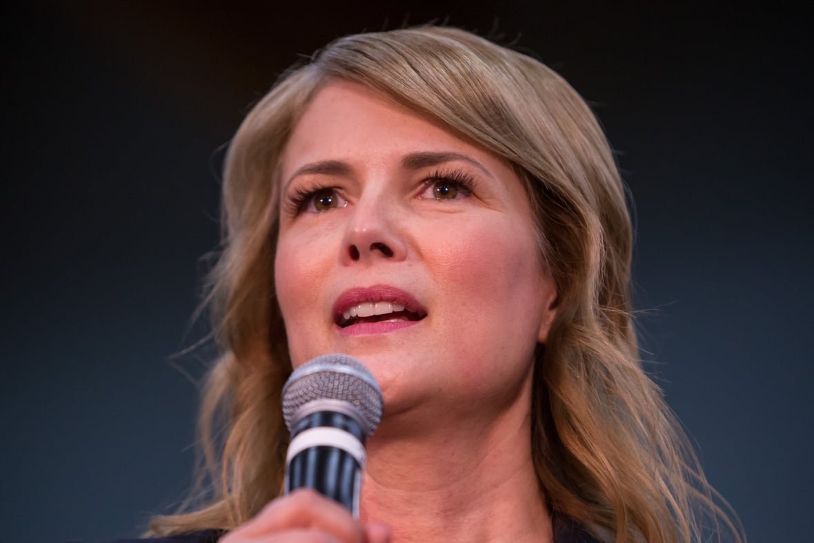 A blond woman speaks into a mic.