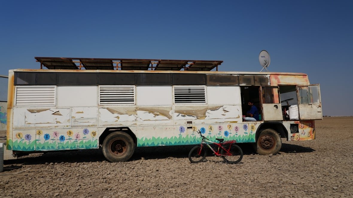 A painted bus sits in a desert.