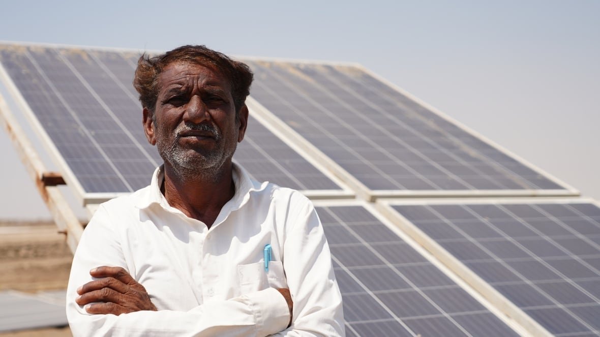 A person stands in front of a solar panel.