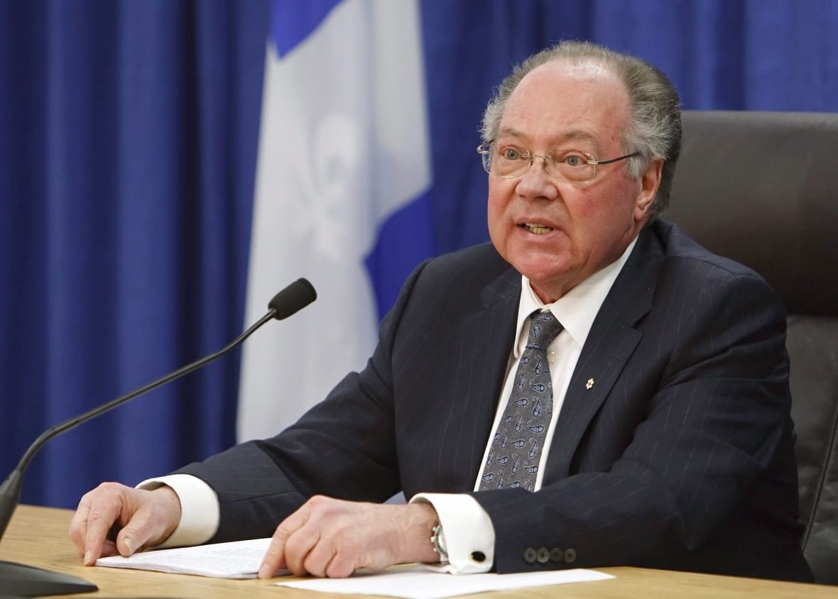 A man sits at a table in front of a microphone.
