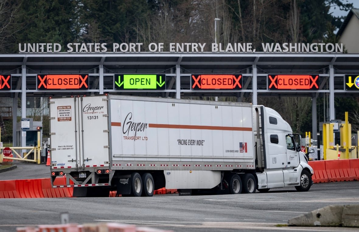 An 18-wheeler truck approaches a border crossing.
