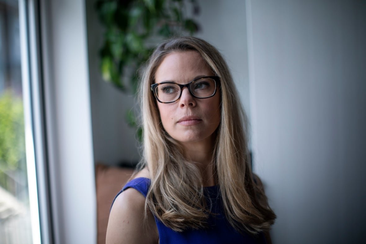 A woman with blond hair and glasses is photographed inside a home.