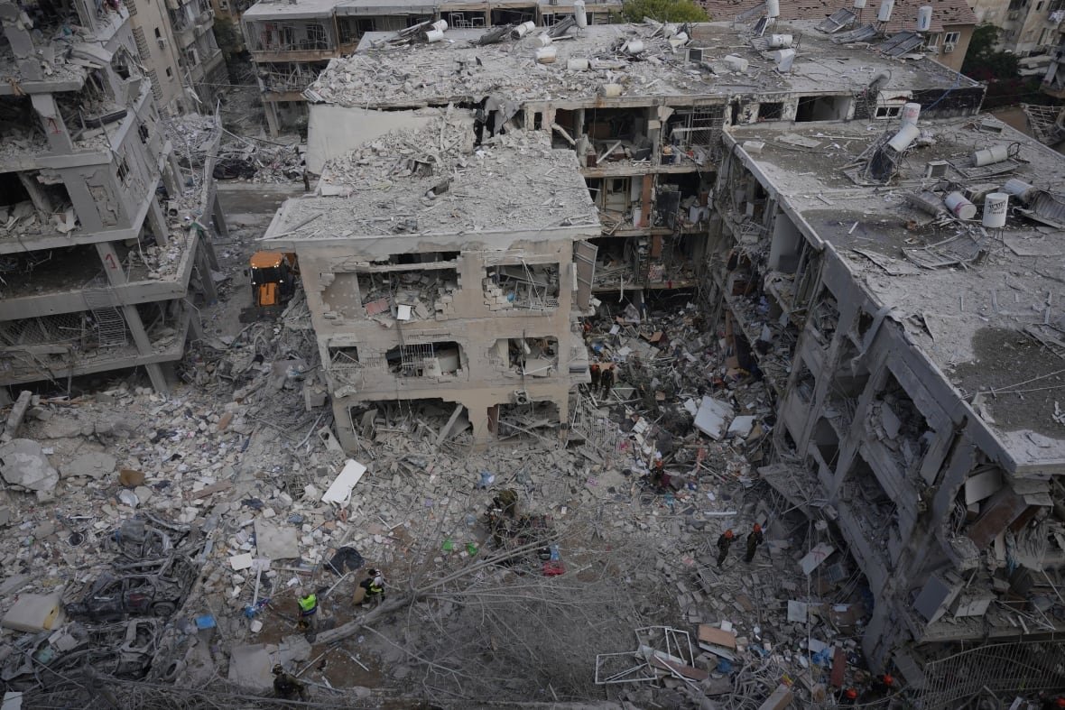 An aerial view shows people gather amid rubble near destroyed buildings.