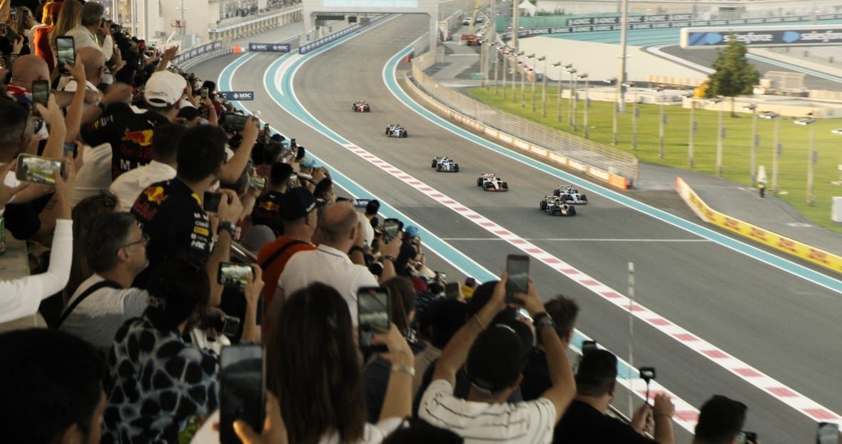 A racing car track with a stand full of fans is shown. 