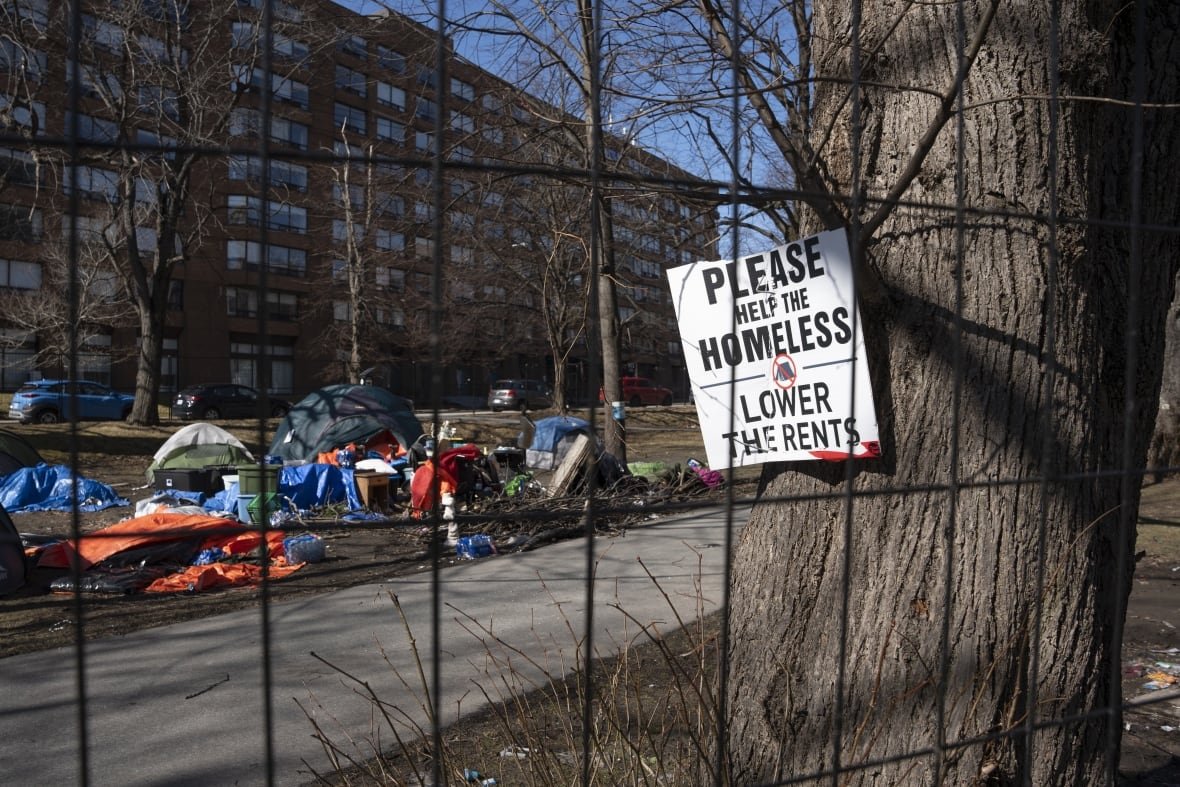 A sign advocating for support for the homeless is seen through a fenced-in homeless encampment in Victoria Park in Halifax on Monday, March 4, 2024
