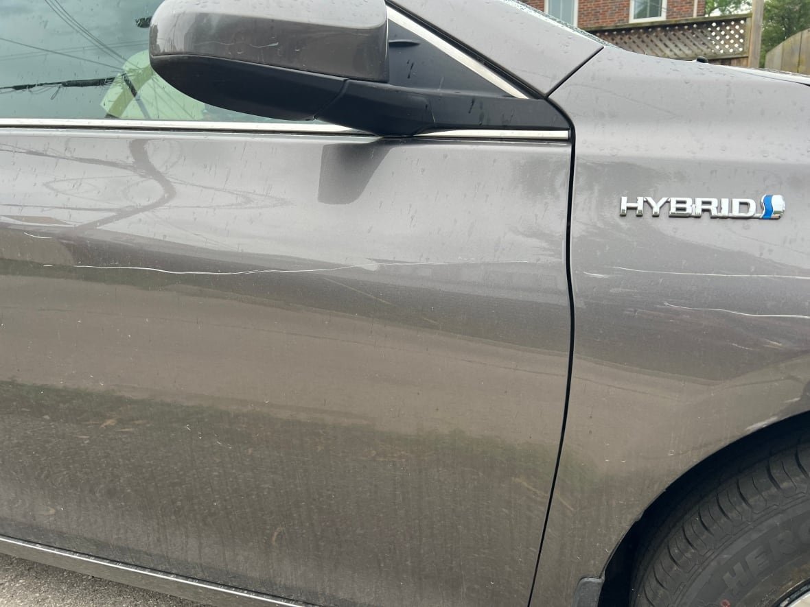 Three large scratches are shown in close up photo of a silver vehicle.