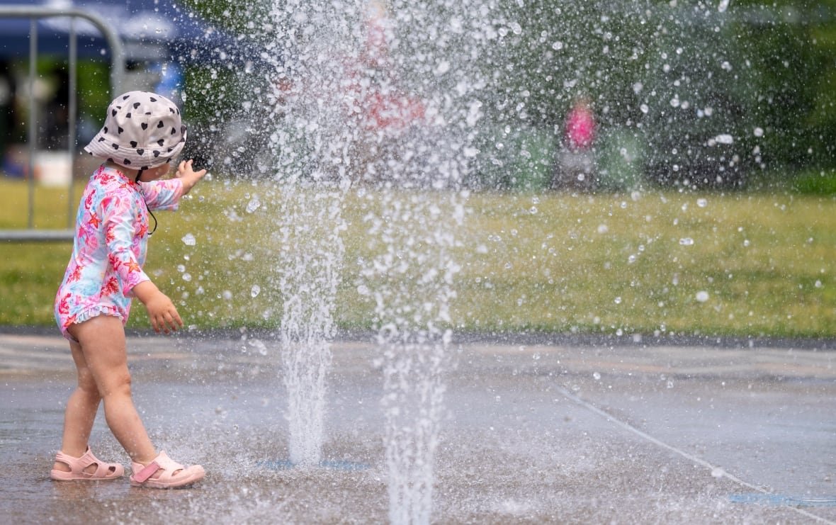 A toddler plays with fountain water at a park.