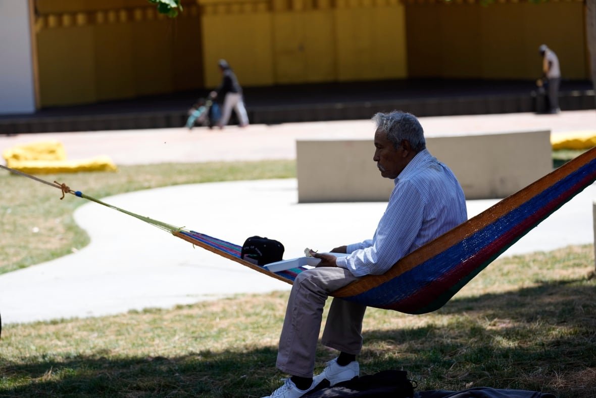 A man sits on a hammock under the shade of a tree as temperatures rise at MacArthur Park, Tuesday, July 11, 2023, in Los Angeles.