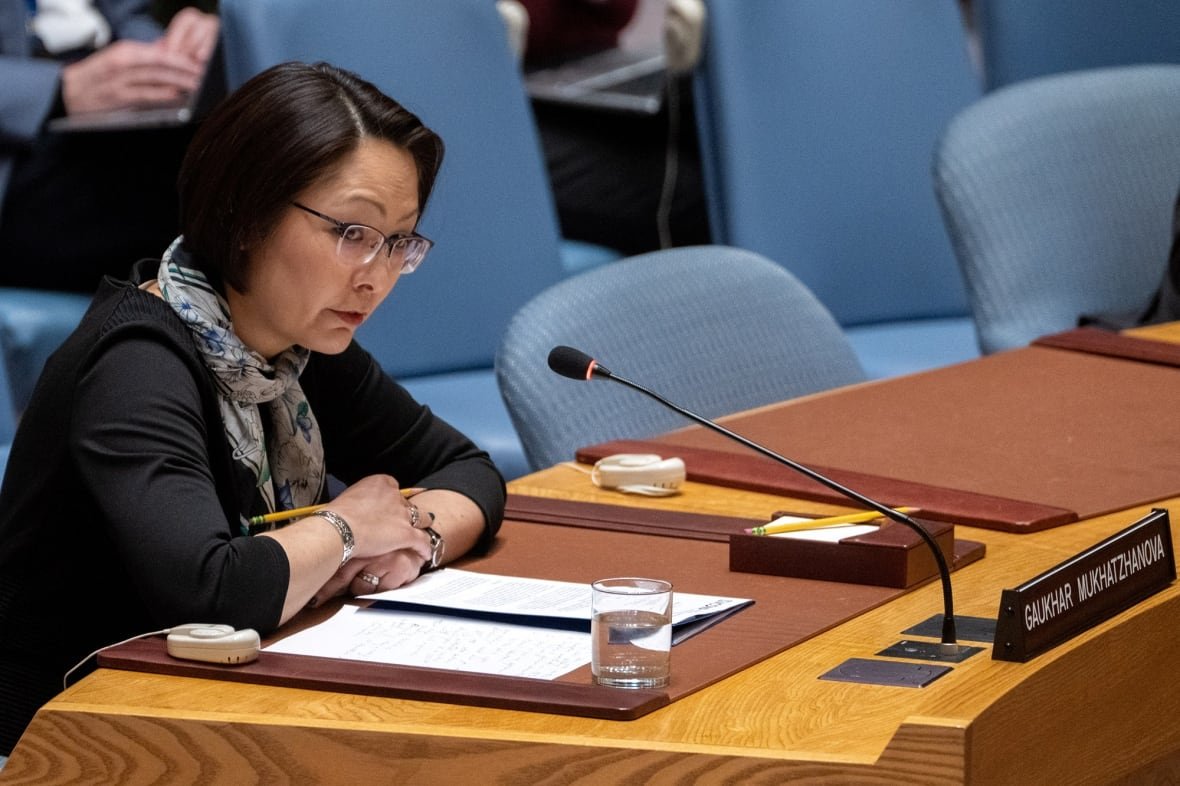 A woman sits at a desk with a microphone.